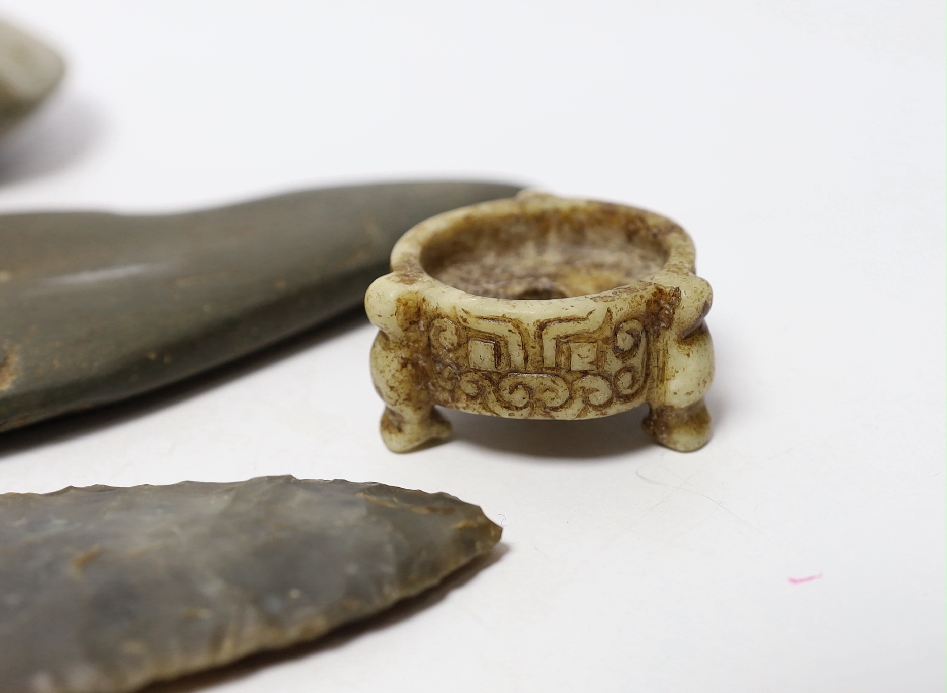 A collection of stone handtools and a Chinese hardstone carving, largest 19cm in length